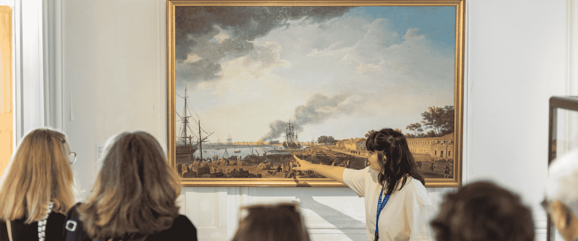 Une guide pointe un élément d'un tableau au Musée national de la Marine
