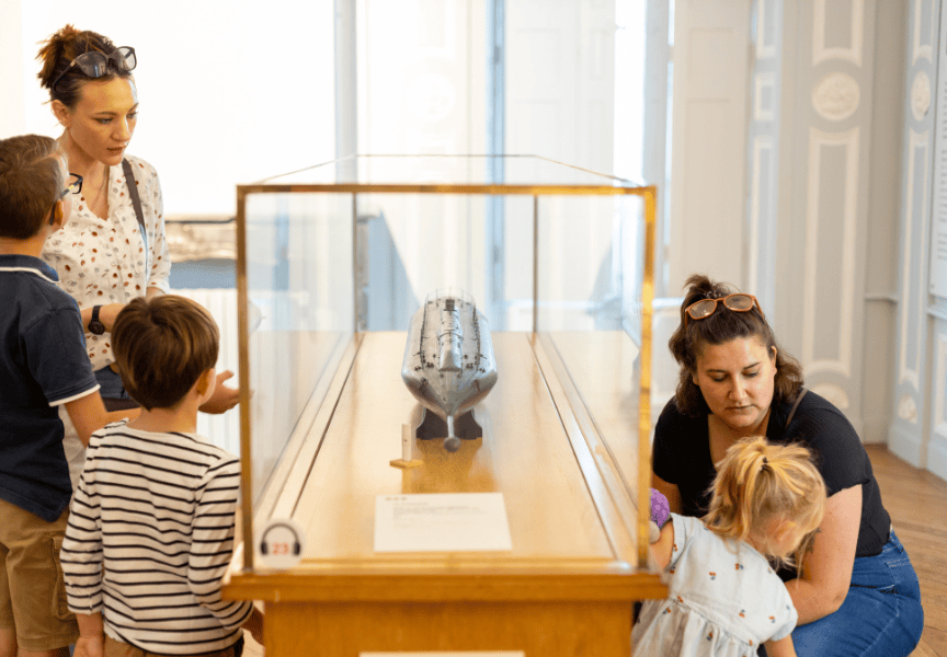 Une famille se tient autour d'une maquette de sous-marin.