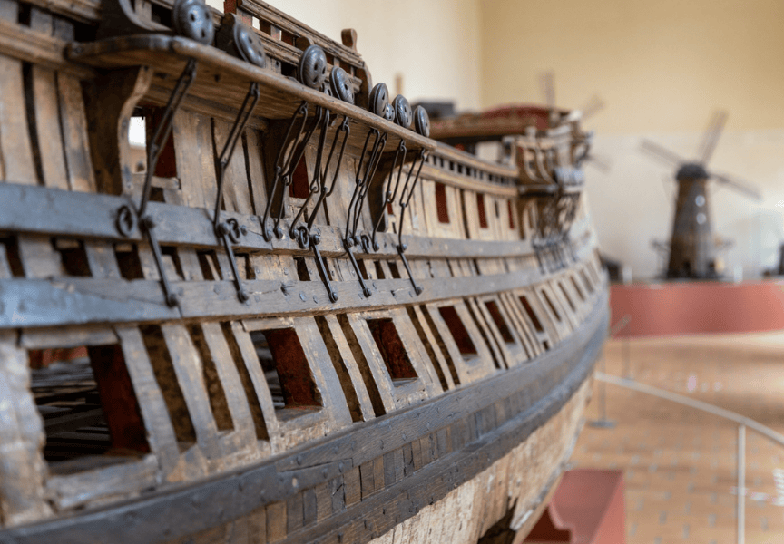 Zoom sur une maquette de bateau avec en arrière-plan un moulin en bois.